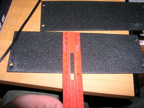 1999 Ford Crown Victoria - A ruler is used to measure the dimensions of two black textured metal plates.