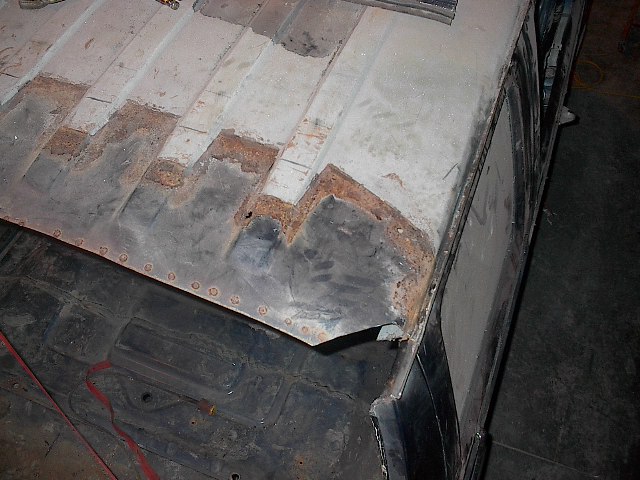 Stripped vehicle roof panel showing rust along ribs and riveted seam during bodywork