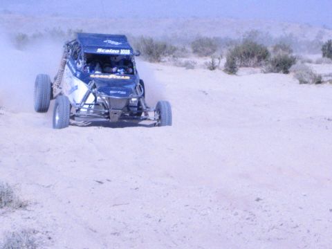 Blue Scalzo number 1018 off-road buggy with Goodyear decals climbing a desert dune