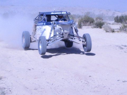 Blue and silver Scalzo 1018 off-road buggy driving toward camera in the desert