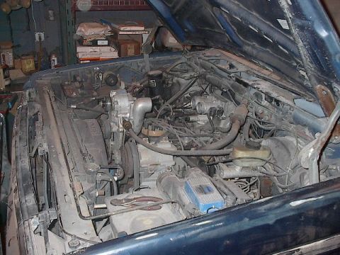 1990 Ford C-350 (Centurion Conversions) - The engine bay of a vehicle is shown with the hood open, revealing various mechanical parts and wiring.