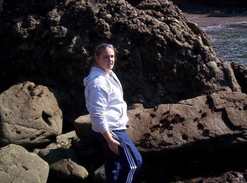1989 Ford Bronco - A woman stands on a rocky shoreline with the ocean in the background.