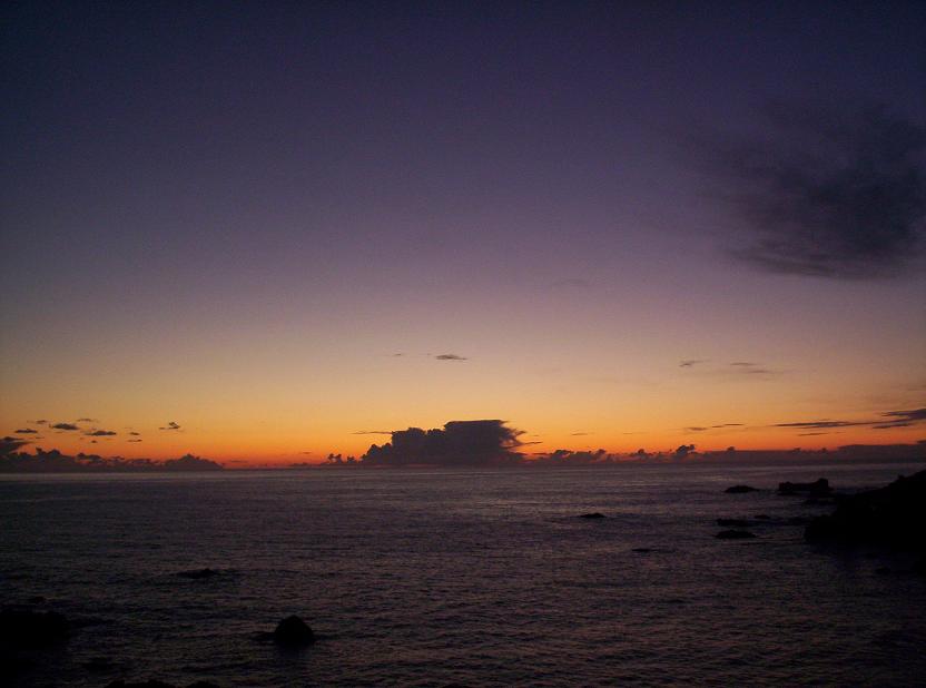 Ocean horizon at sunset with purple and orange sky and dark water