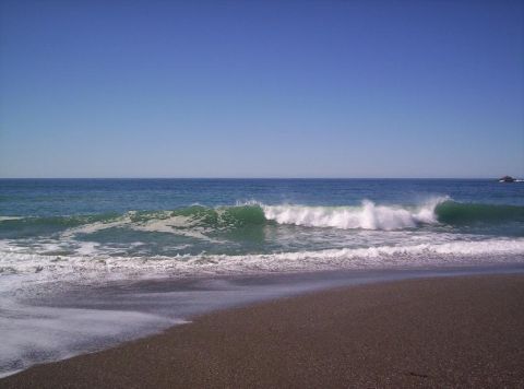 1989 Ford Bronco - Waves roll onto the shore on a sunny day at the beach.