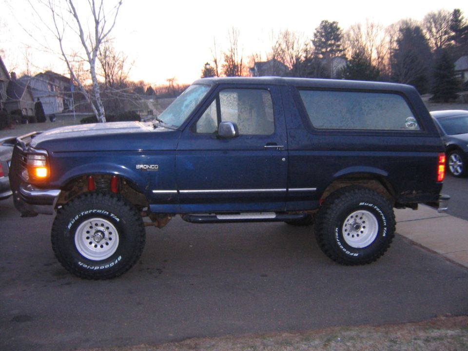 Lifted dark blue Ford Bronco side profile on BFGoodrich mud-terrain tires at dusk
