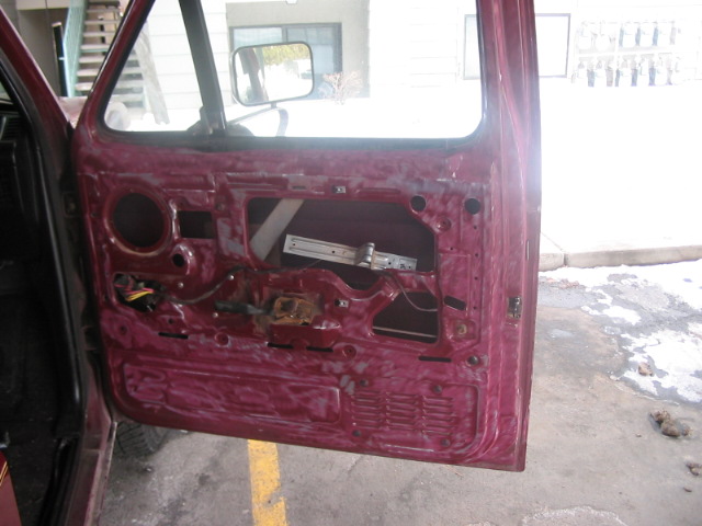 Disassembled car door interior showing window mechanism and wiring. Maroon exterior paint