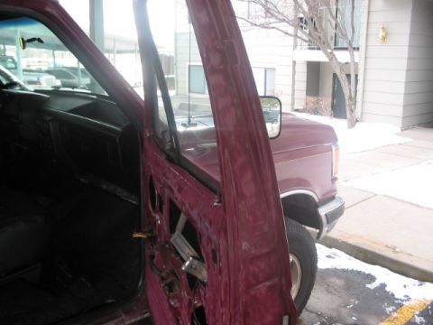1991 Ford Bronco - The interior of a maroon truck is visible with the driver's door open, revealing the removed door panel and dashboard components.