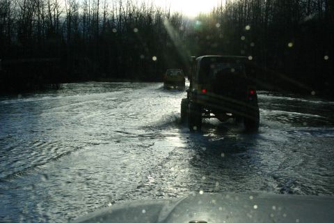 2003 Jeep TJ - Two Jeep TJs navigate a shallow body of water, kicking up spray as they drive through the scene.