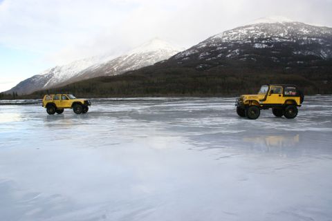 2003 Jeep TJ - Two yellow Jeep TJs parked on a frozen lake with snow-capped mountains behind them.