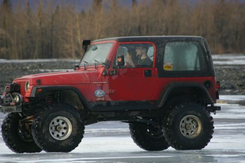 2003 Jeep TJ - Red 2003 Jeep TJ Wrangler with black hardtop on ice, likely in a cold climate.
