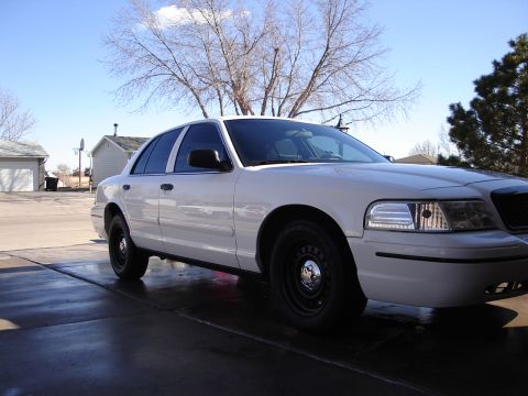 2000 Ford Crown Victoria - A white 2000 Ford Crown Victoria sedan is parked in a driveway on a sunny day.