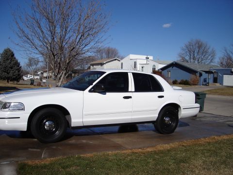 2000 Ford Crown Victoria - A white 2000 Ford Crown Victoria is parked on a driveway with houses in the background.