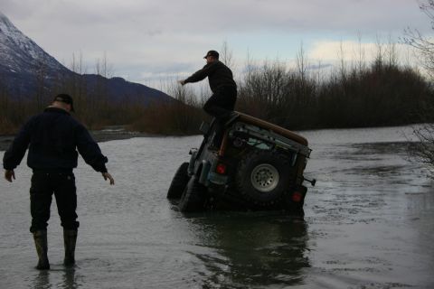2003 Jeep TJ - A 2003 Jeep TJ is stuck in the water, with two individuals observing the situation.
