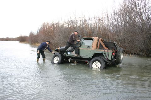2003 Jeep TJ - Two men attempt to free a Jeep Wrangler that is partially submerged in a body of water.