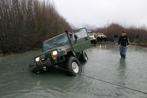 2003 Jeep TJ - A group of Jeeps navigate a flooded area, with one vehicle appearing to be stuck.