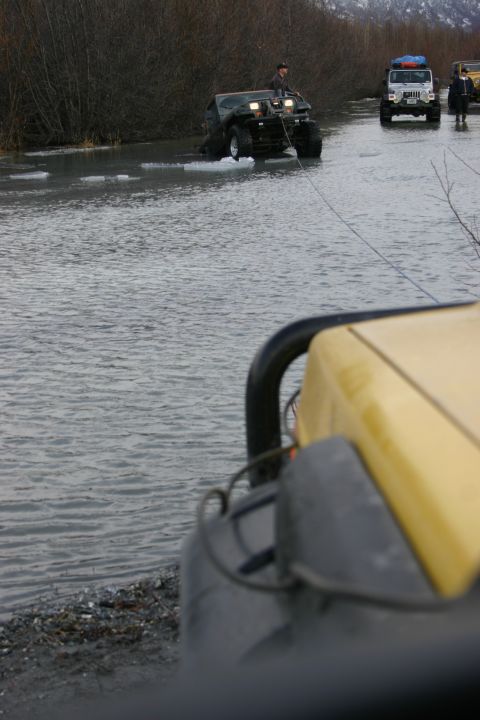 2003 Jeep TJ - A Jeep TJ is being towed through shallow water, with another Jeep and a person in the background.