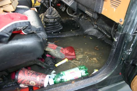 2003 Jeep TJ - The interior of a vehicle is submerged in water, with various items floating on the surface.