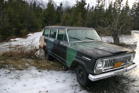 2003 Jeep TJ - A Jeep Wagoneer with a camouflage paint job sits on a dirt road in a snowy, forested area.