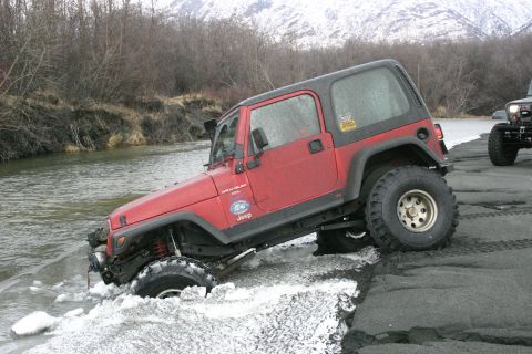 2003 Jeep TJ - Red 2003 Jeep TJ Wrangler navigating icy water near a snowy bank.