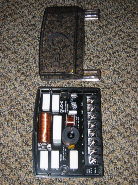 1995 Ford Bronco - A car stereo crossover component is shown with its protective cover removed, revealing internal circuitry.