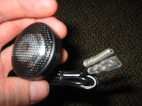 1995 Ford Bronco - A car speaker with attached wires is held in a hand against a textured background.