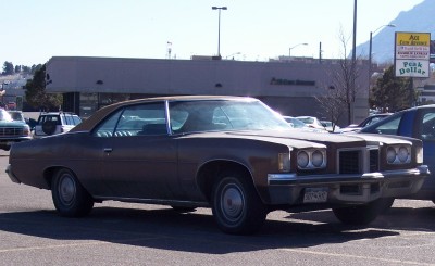 1972 Ford Ranchero - This brown coupe features a distinctive grille and quad headlights, seen parked in a lot with other vehicles.