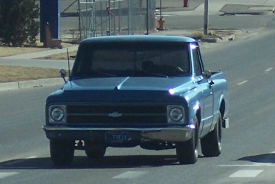 1972 Ford Ranchero - A blue pickup truck drives down the road, its front end clearly visible.