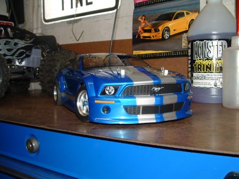 1994 Ford Bronco - A blue remote control car with silver racing stripes is displayed next to a toy monster truck.