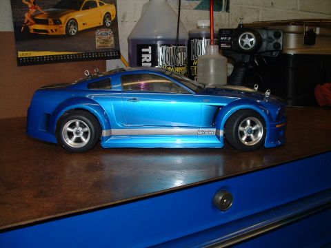1994 Ford Bronco - A blue remote control car sits on a workbench next to hobby supplies and a poster.