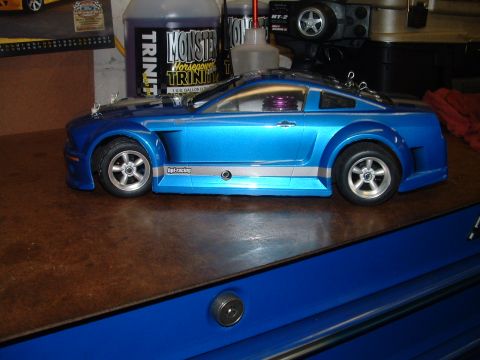 1994 Ford Bronco - A blue remote control car with silver racing stripes sits on a wooden surface.