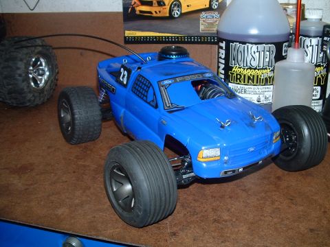 1994 Ford Bronco - A blue RC monster truck is displayed on a workbench next to bottles of fuel.
