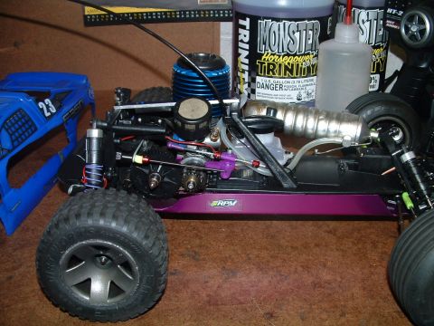 1994 Ford Bronco - RC car chassis with engine and exhaust components, next to a blue body shell.