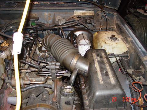 2004 Jeep Wrangler - The engine bay of a Jeep is shown, the air intake tube and power steering reservoir.