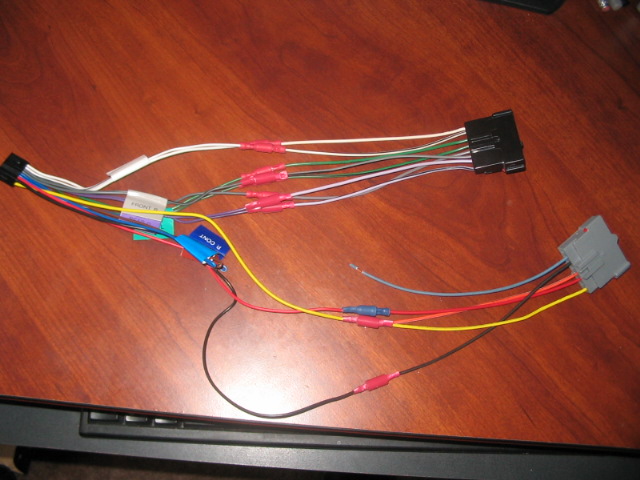 Wiring harness with black and gray connectors, red crimp connectors, and a blue component