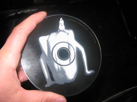 1991 Ford Bronco - A hand holds a CD a stylized white figure against a dark background.
