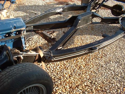 1964 Ford Galaxie - Close-up of a vehicle's chassis and engine components on a gravel surface.