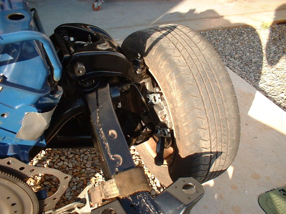 Restored black front suspension and tire on a light-blue frame during a chassis rebuild