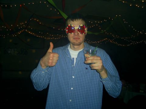 1977 Ford F-150 - A man wearing oversized, colorful glasses and holding a drink gives a thumbs-up gesture.