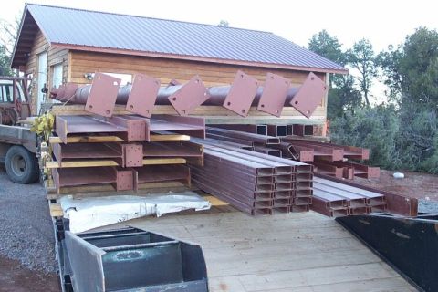 1986 Ford Ranger - A flatbed trailer is loaded with various steel construction materials, including I-beams and channel beams.