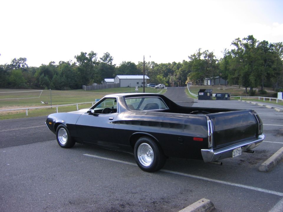 Black Ford Ranchero car-pickup, rear 3/4 view in a parking lot