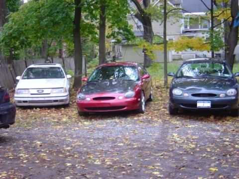 1998 Ford Taurus - Three Ford Taurus sedans are parked in a yard during autumn.