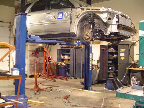 1994 Ford Bronco - Vehicle undergoing repairs on a lift in a workshop, with front end removed.