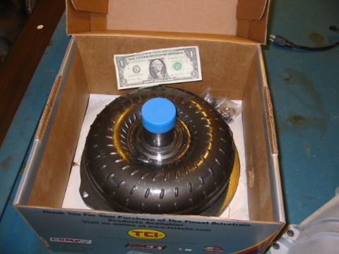 1985 Ford Crown Victoria LTD - A torque converter is shown inside its shipping box, with a dollar bill for scale and a small bag of hardware.