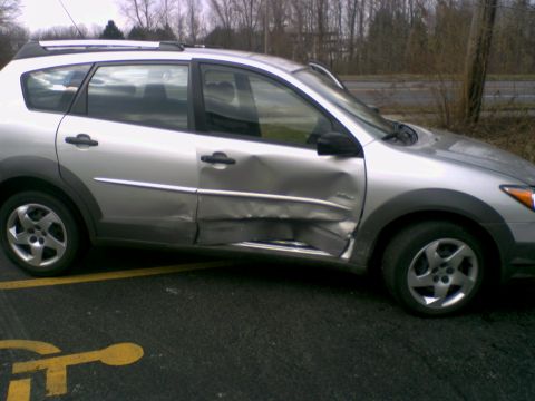 1995 Ford Bronco - The side of a silver hatchback shows severe damage to the front and rear doors and the lower body panel.