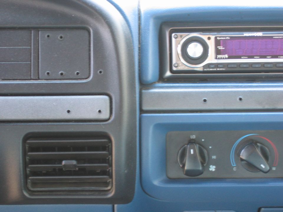 Dash center stack with aftermarket Kenwood Sirius stereo, air vent, and HVAC knobs on blue trim