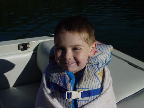 1986 Ford Bronco - A young child smiles while bundled in a towel and life jacket on a boat, with dark water behind them.