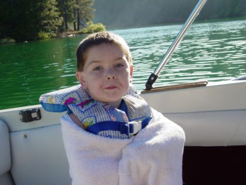 1986 Ford Bronco - A young boy is wrapped in a towel and wearing a life vest while on a boat trip across a lake.