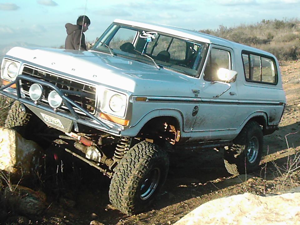 Light blue 1978 Ford Bronco with off-road modifications climbing rocks
