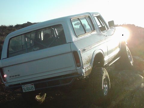 1978 Ford Bronco - This 1978 Ford Bronco is captured in a rear 3/4 view while navigating rocky terrain under a bright sun.