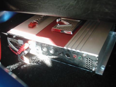 1978 Ford Bronco - A car stereo amplifier is installed under the seat, red and silver detailing and various input/output connections.